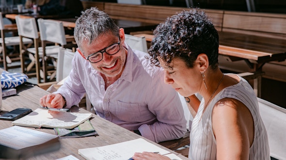 A photo of two people talking and writing.